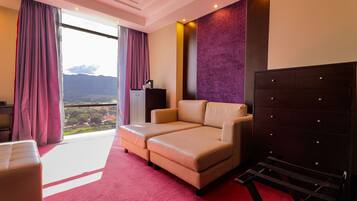 Habitación de hotel con sofá, escritorio, cómoda y vistas a la montaña.