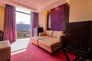 A hotel room with a sofa, a desk, a dresser, and a view of the mountains. - Hotel Hesperia de Valencia (Naguanagua)