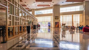 A spacious lobby with a checkered floor, a seating area with colorful chairs, and a large window providing natural light.