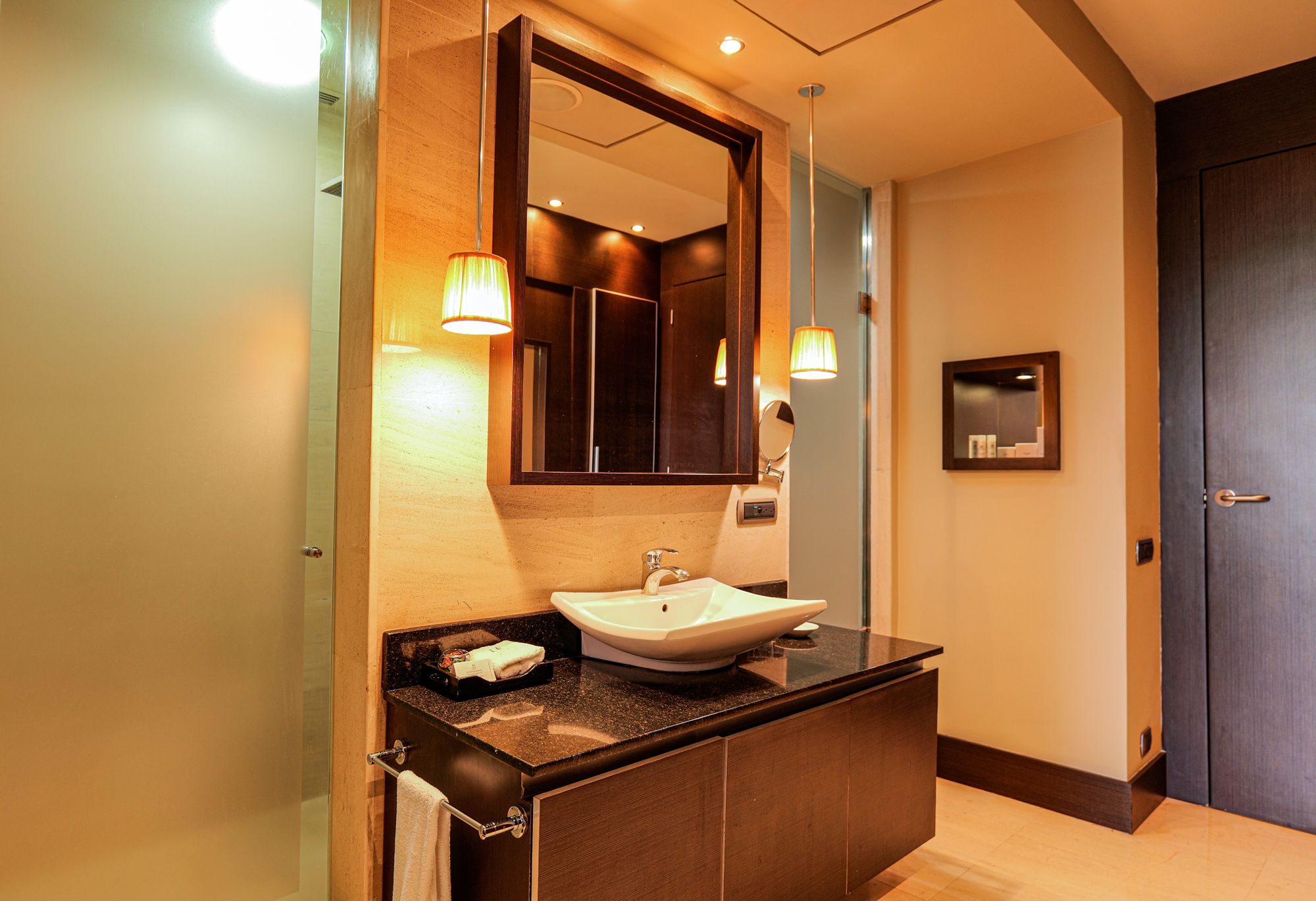 A modern bathroom with a large mirror, a sink, and two wall-mounted lights.