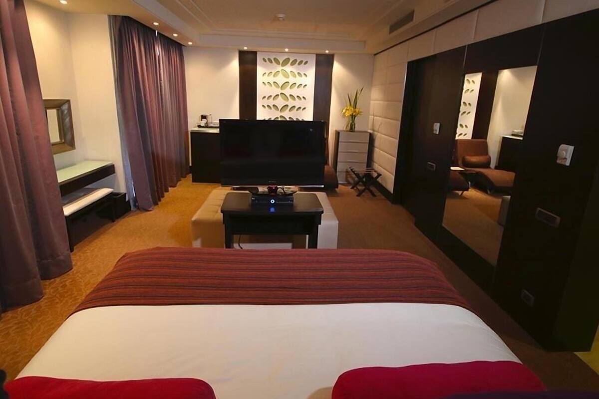Een hotelkamer met een bed, een televisie, een bureau en een spiegel.