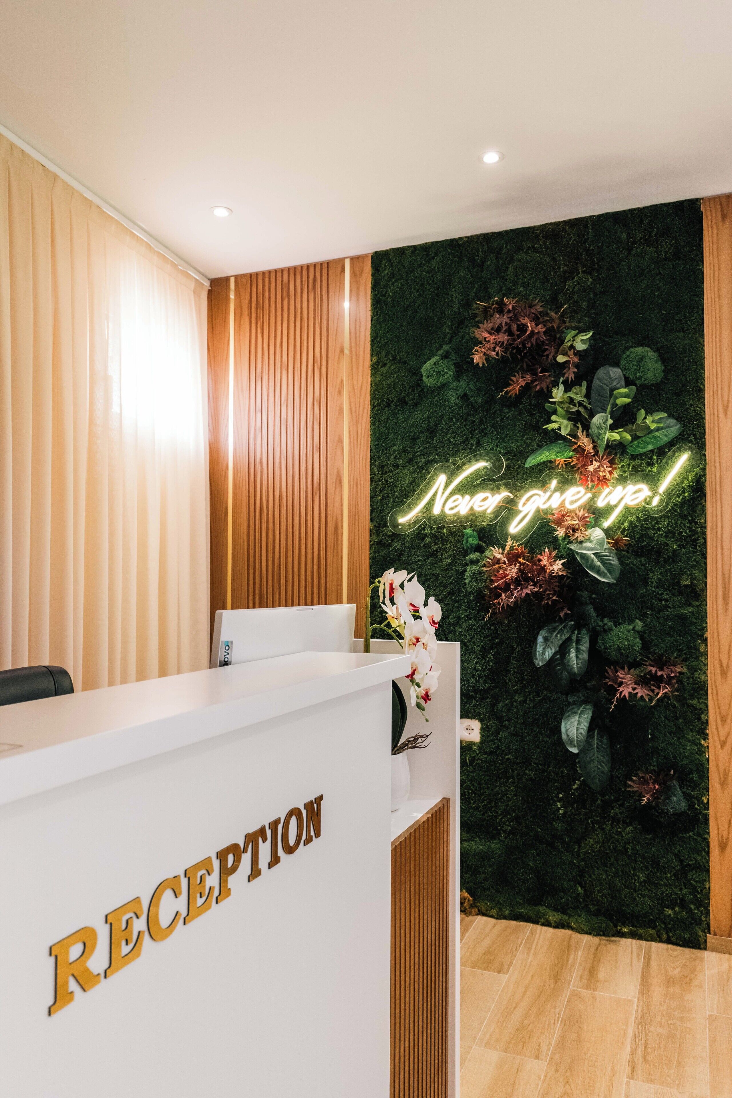 Un área de recepción con un revestimiento de panel de madera, un letrero de neón que dice "Never give up!" y un mostrador de recepción.