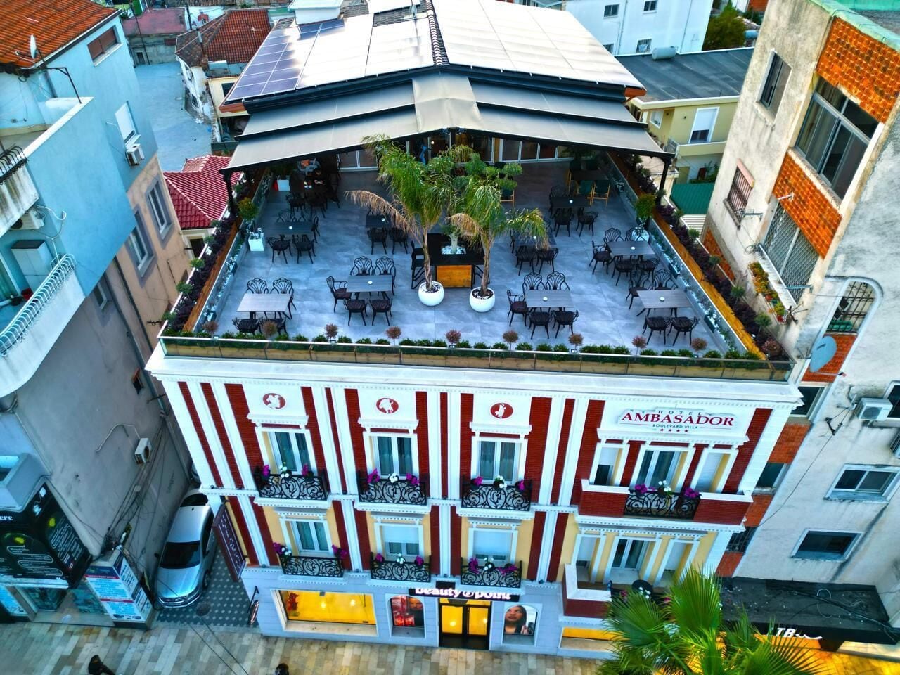 Un hotel con terraza en la azotea que cuenta con asientos al aire libre y un jardín central con palmeras.