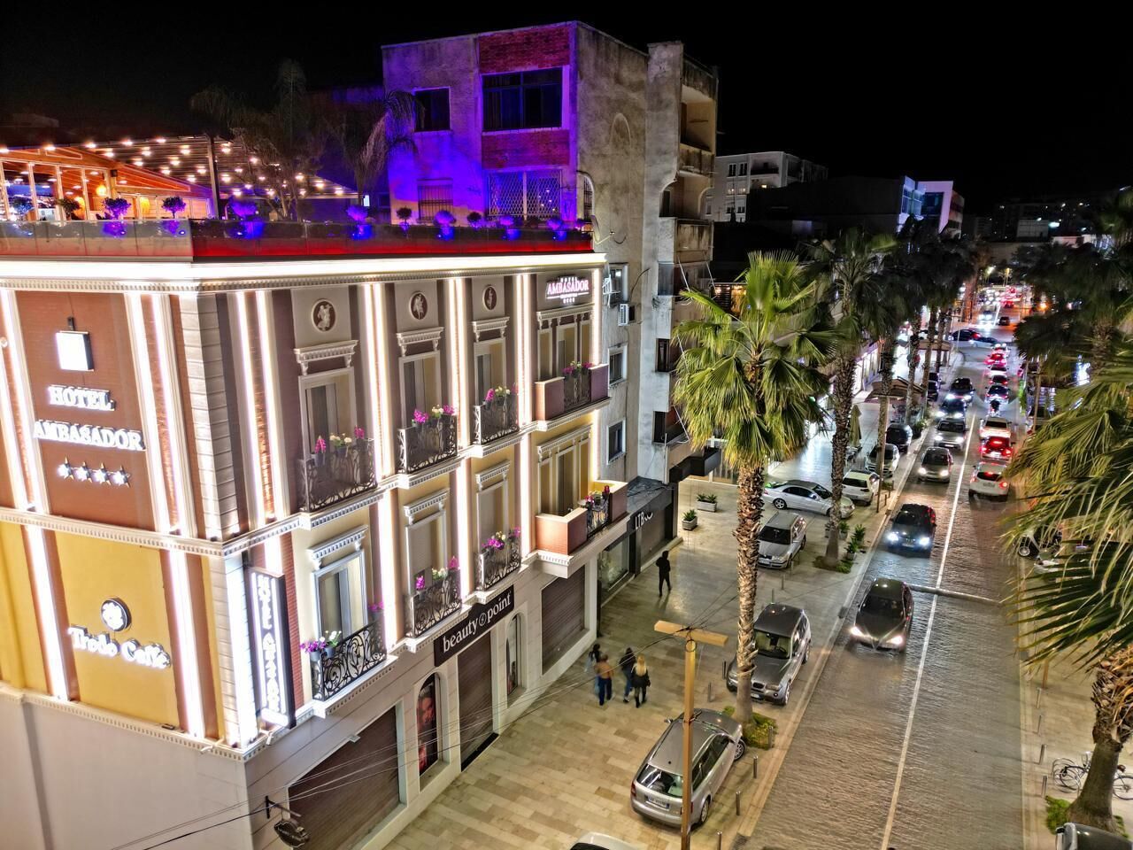 Un hotel amb múltiples pisos, balcons i diverses botigues a la planta baixa.