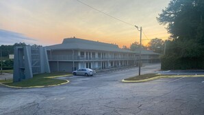 A motel with a large parking lot, a single-story building, and a grassy area. - 1st Place at Wesley (Decatur)
