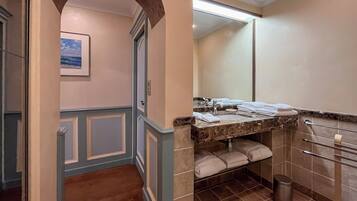 A bathroom with a marble countertop, a sink, a towel rack, and a trash can.