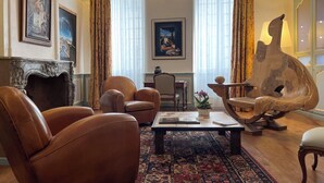 A spacious living room with leather armchairs, a coffee table, and a unique sculpture. - Chambre d'Art (Dax)