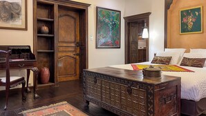 A bedroom with a large bed, wooden furniture, and artwork on the walls. - Chambre d'Art (Dax)