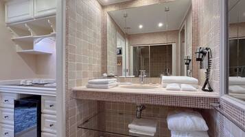 A modern bathroom with a large mirror, a sink, and a glass shower enclosure.