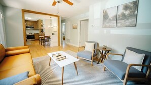 A living room with a sofa, armchair, coffee table, and a ceiling fan. - Home in Carrboro, Fully Renovated! (Carrboro)