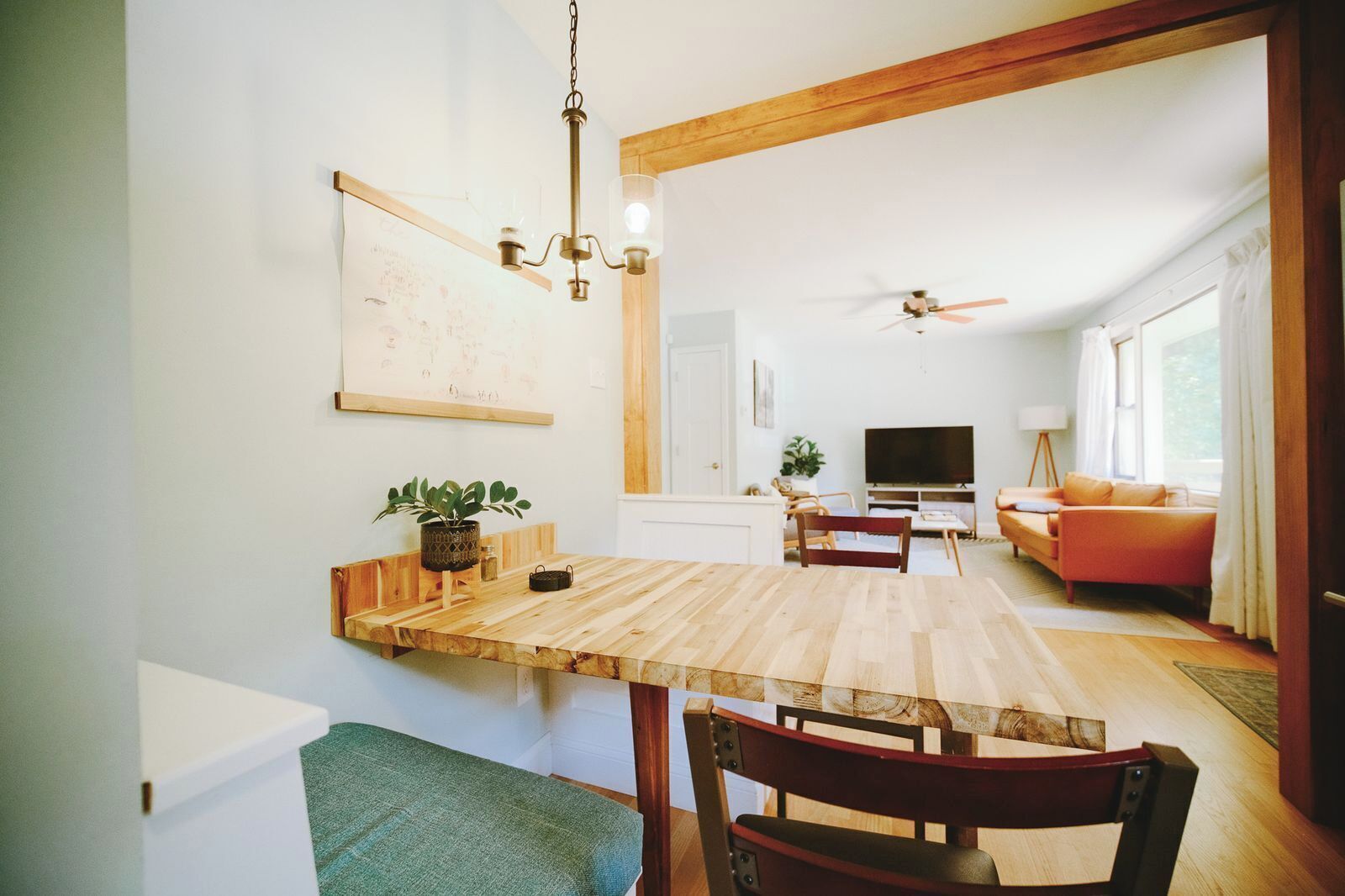 Ein Essbereich mit Holztisch, Stühlen, einer Hängeleuchte und einem Gemälde an der Wand.