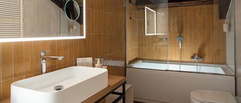 A modern bathroom with a large white sink, a bathtub, and a toilet.