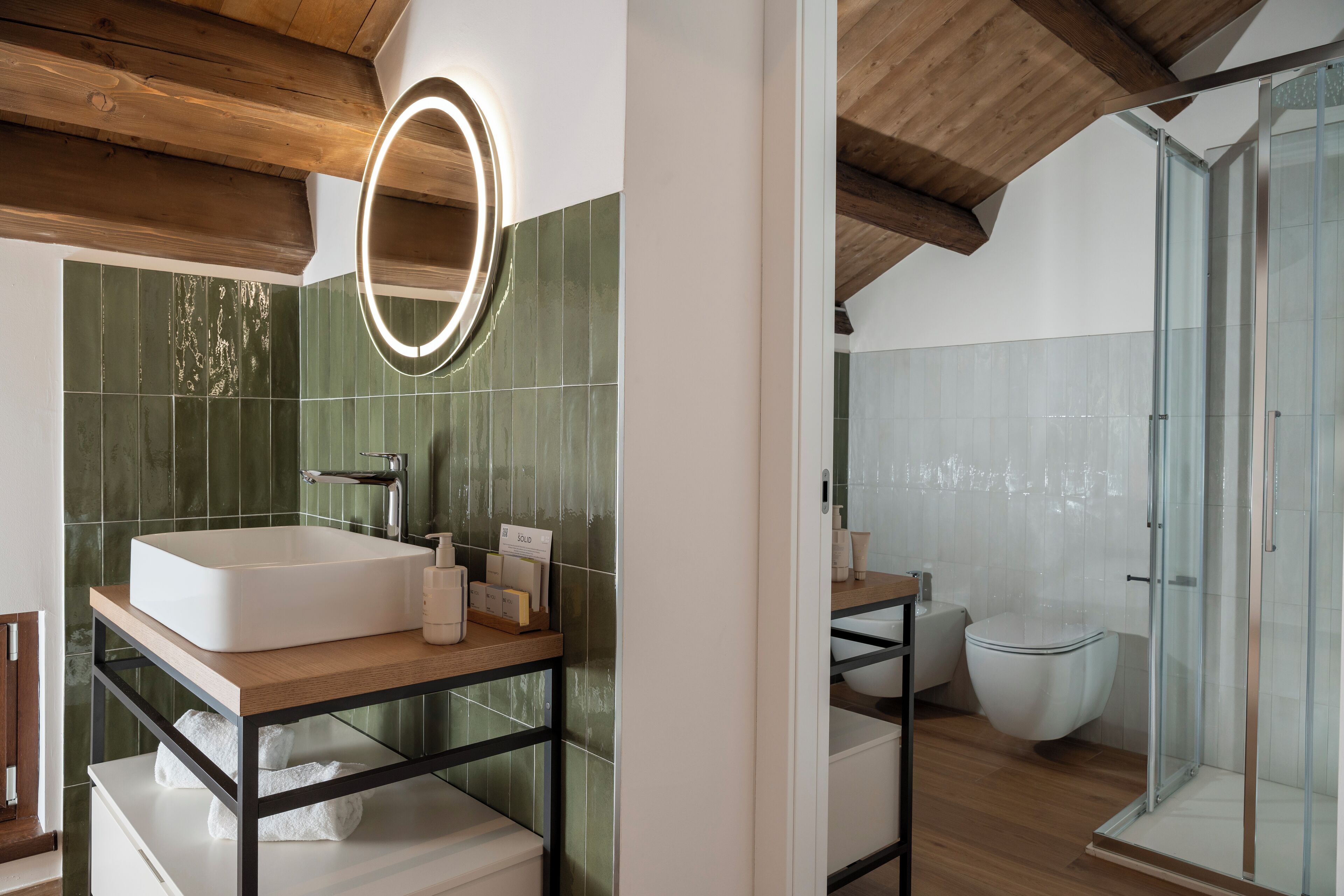 A modern bathroom with a freestanding sink, a glass shower enclosure, and a wooden ceiling.