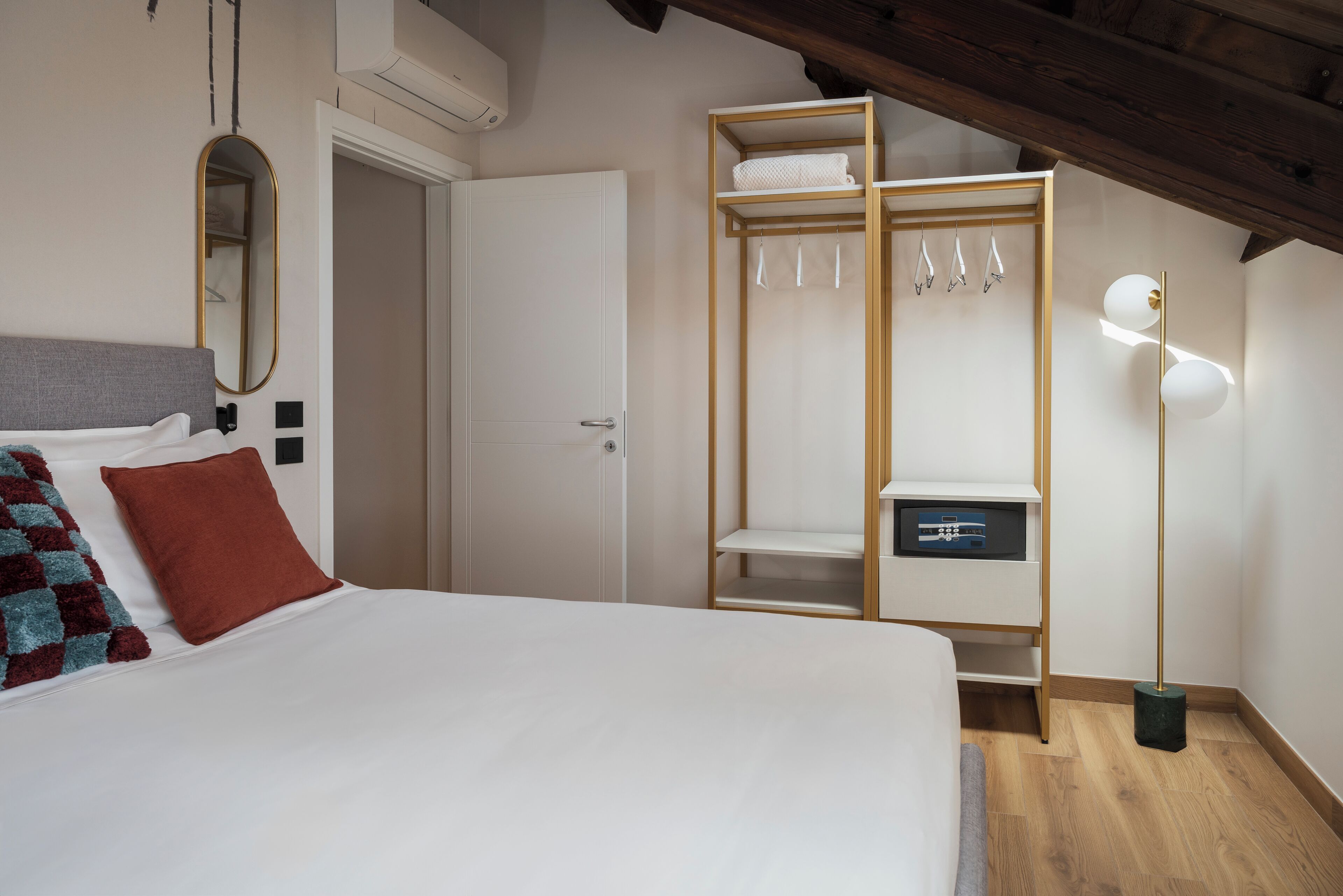 Un dormitorio con cama, armario, espejo y lámpara de pie.