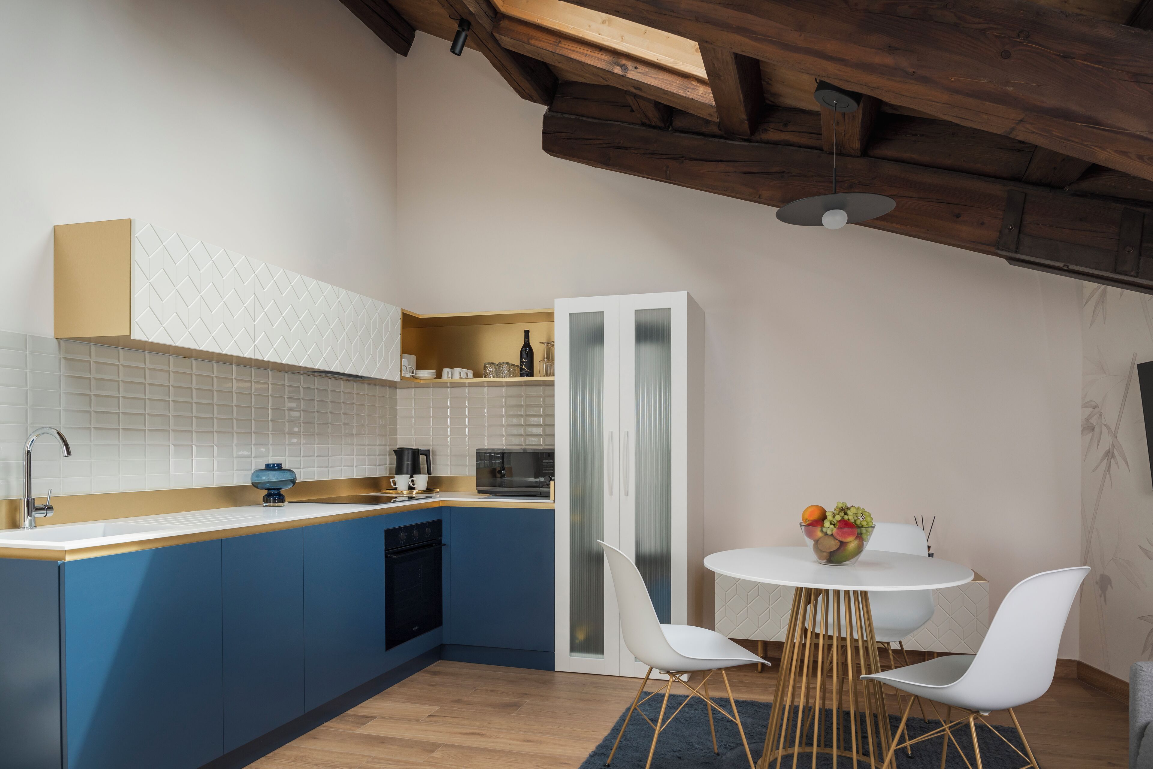 Una cocina moderna con armarios azules, encimera blanca y techo de madera.