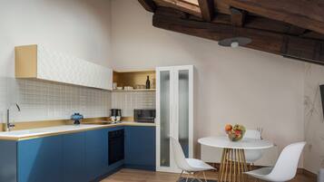 Una cocina moderna con armarios azules, encimera blanca y techo de madera.