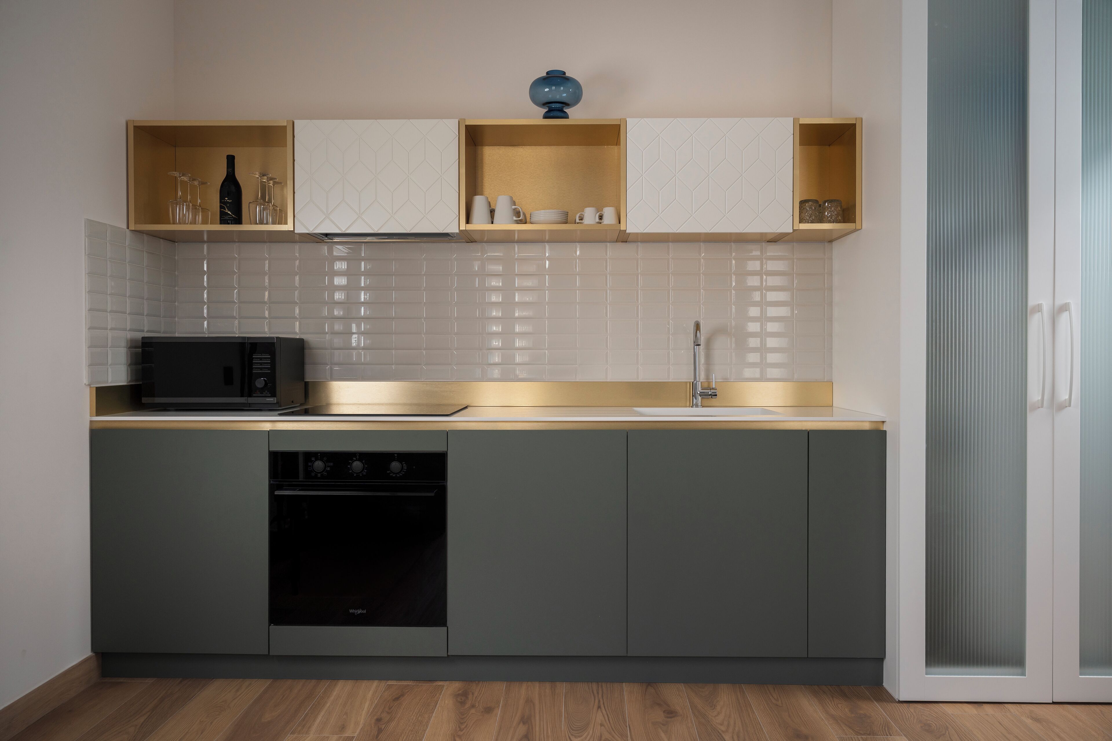 A modern kitchen with a microwave, dishwasher, and wooden shelves above the counter.