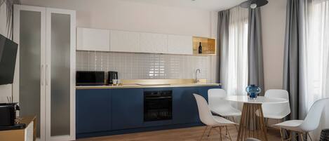 A modern kitchen with a blue island, white cabinets, and a dining area with white chairs and a round table.