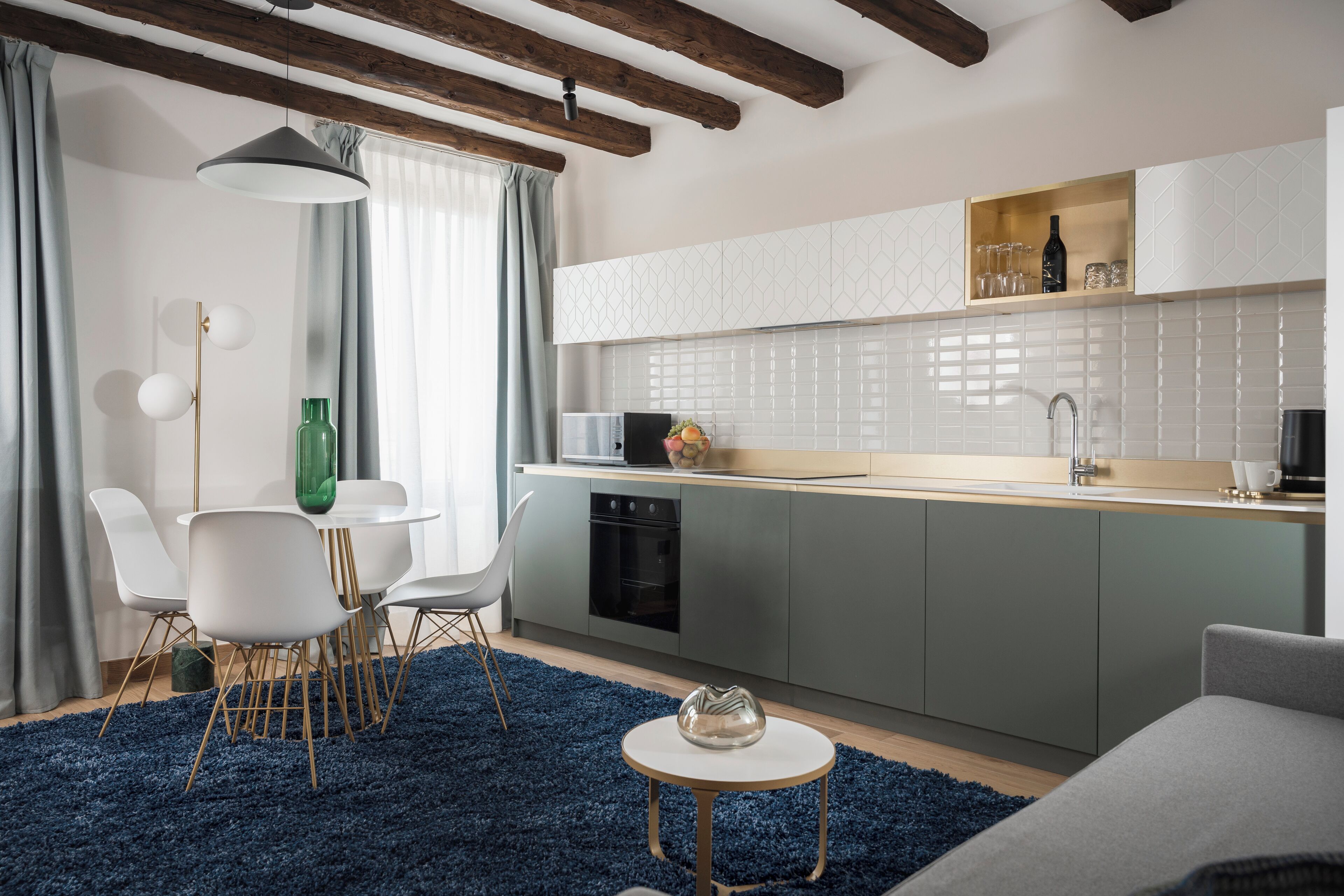 Une cuisine moderne dotée d’un îlot central intégré, de meubles blancs et d’un coin repas avec une table ronde et des chaises.