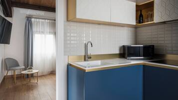 Una cocina moderna con microondas integrado, un lavamanos y una pequeña mesa redonda.