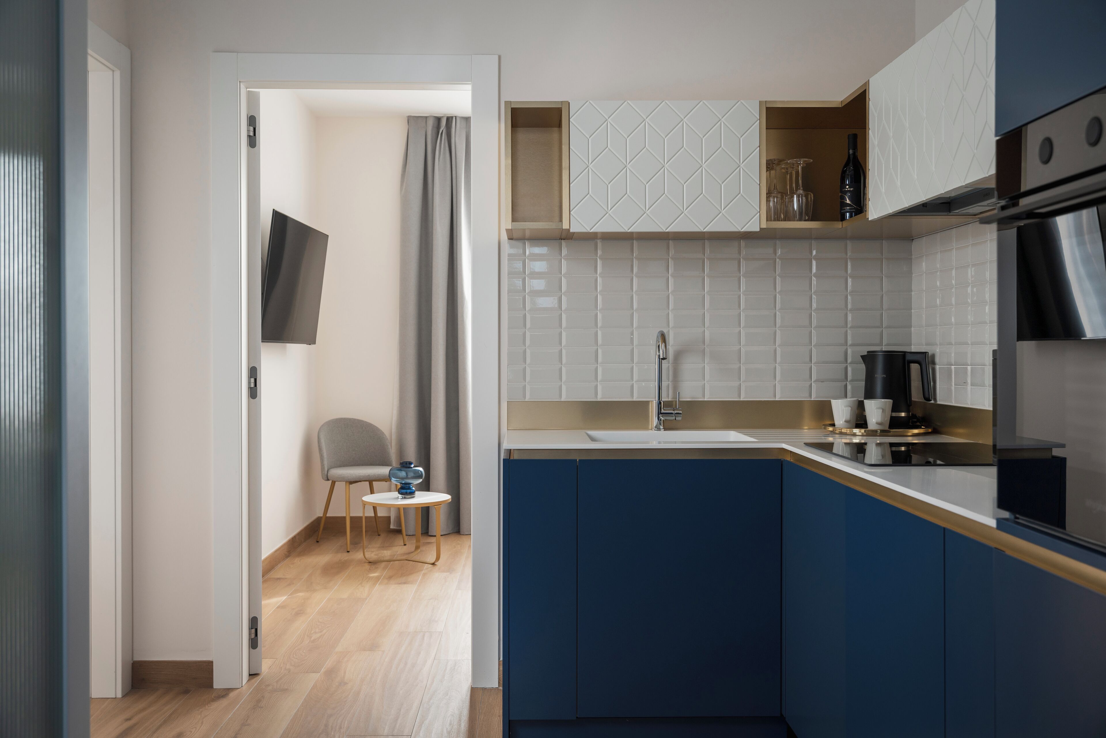Una cocina moderna con armarios azules, encimera blanca y horno integrado.