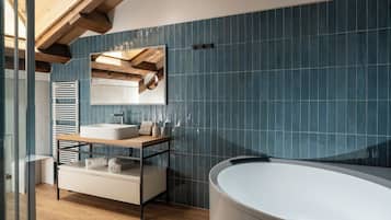 Un baño moderno con una bañera independiente, un lavamanos con espejo y un banco de madera.