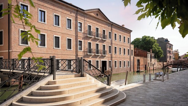 A brick building with a staircase leading to a canal. - Palazzo Dei Guardiani (Venice)