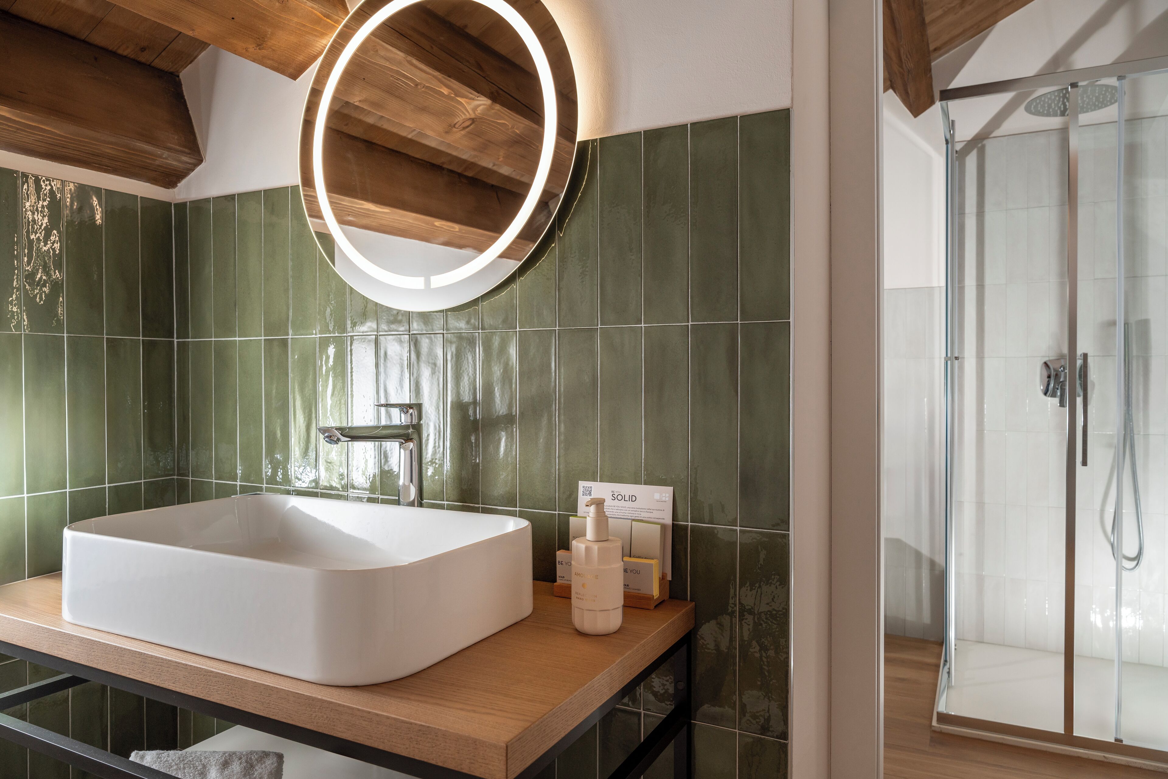 Un baño con un lavamanos grande y rectangular, un espejo con luz circular y zona de ducha.