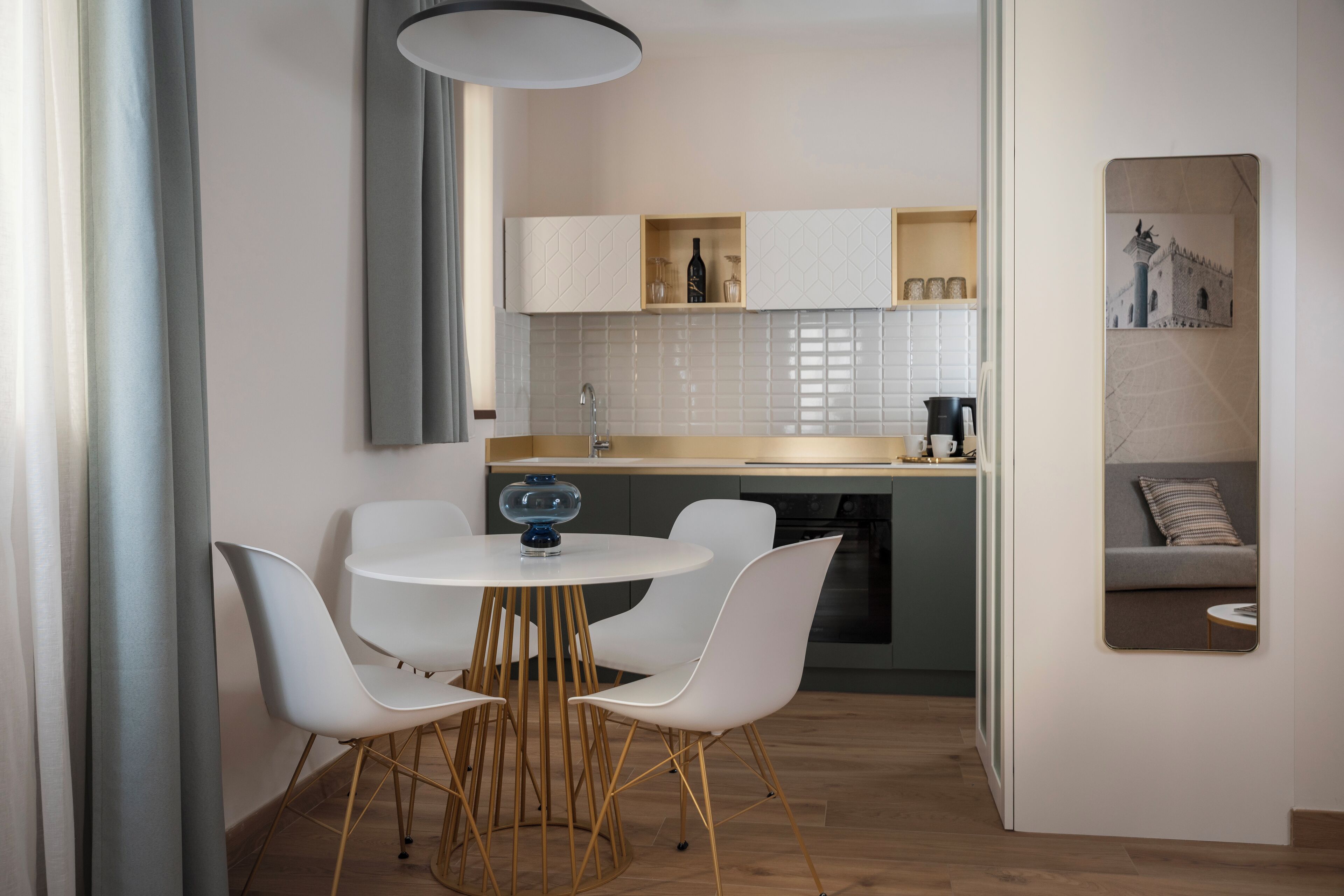Una cocina moderna con armarios blancos, una mesa redonda de comedor con sillas blancas y un horno empotrado.
