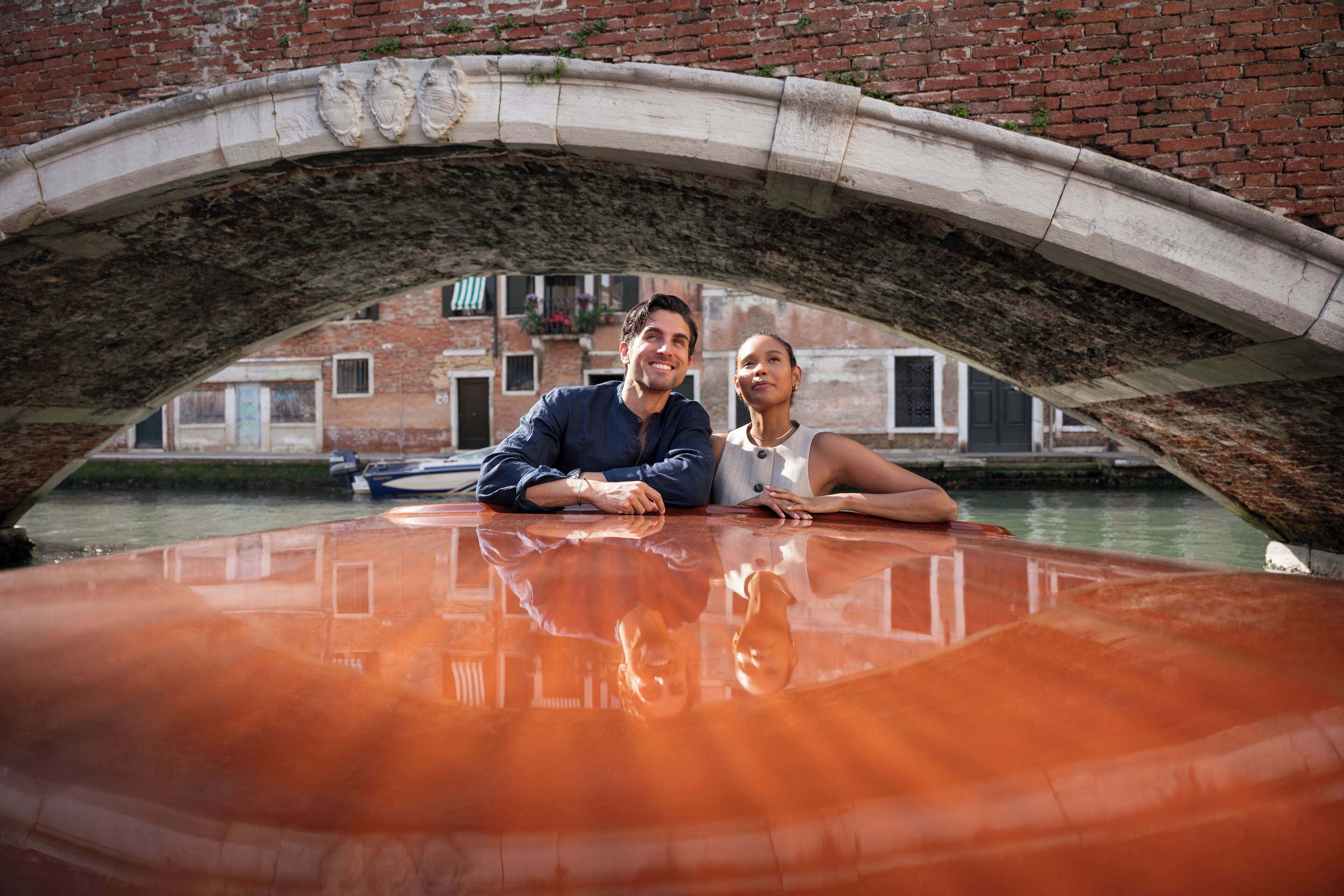 A couple under a bridge with a boat in the foreground.