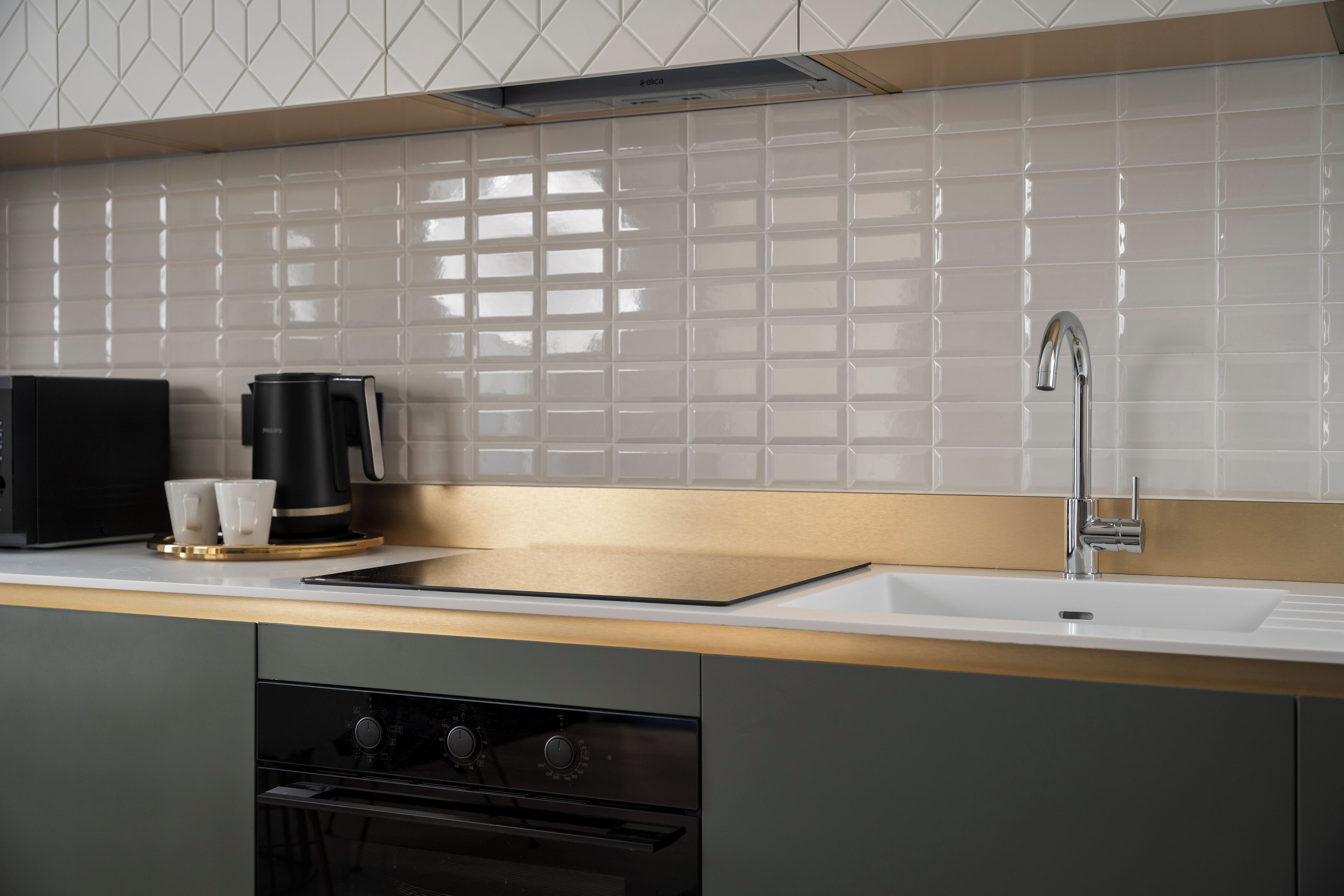 Una cocina moderna con un lavamanos de acero inoxidable, una cafetera y un horno empotrado.