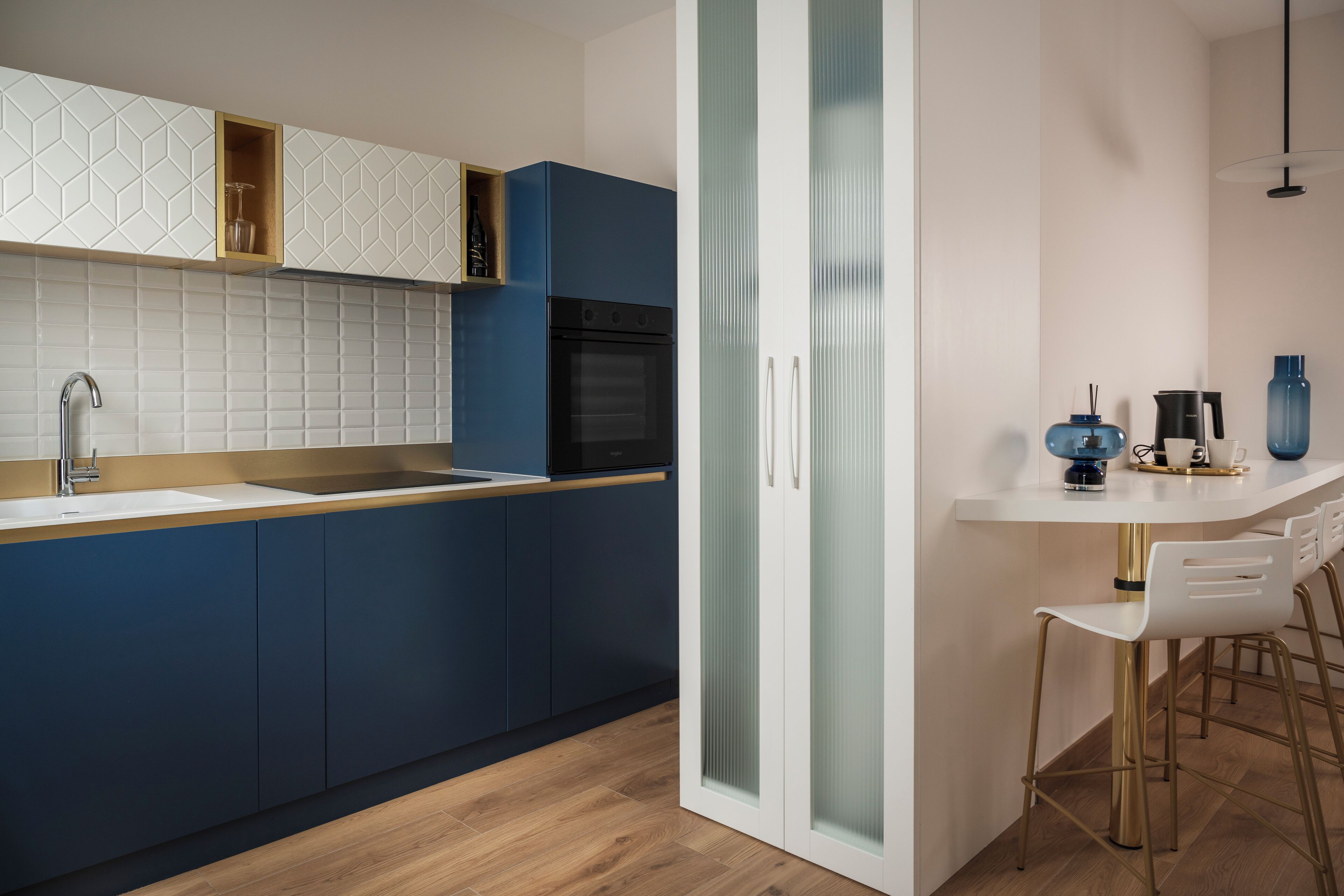 Een moderne keuken met een inbouwoven, een spoelbak en een bar met barkrukken.
