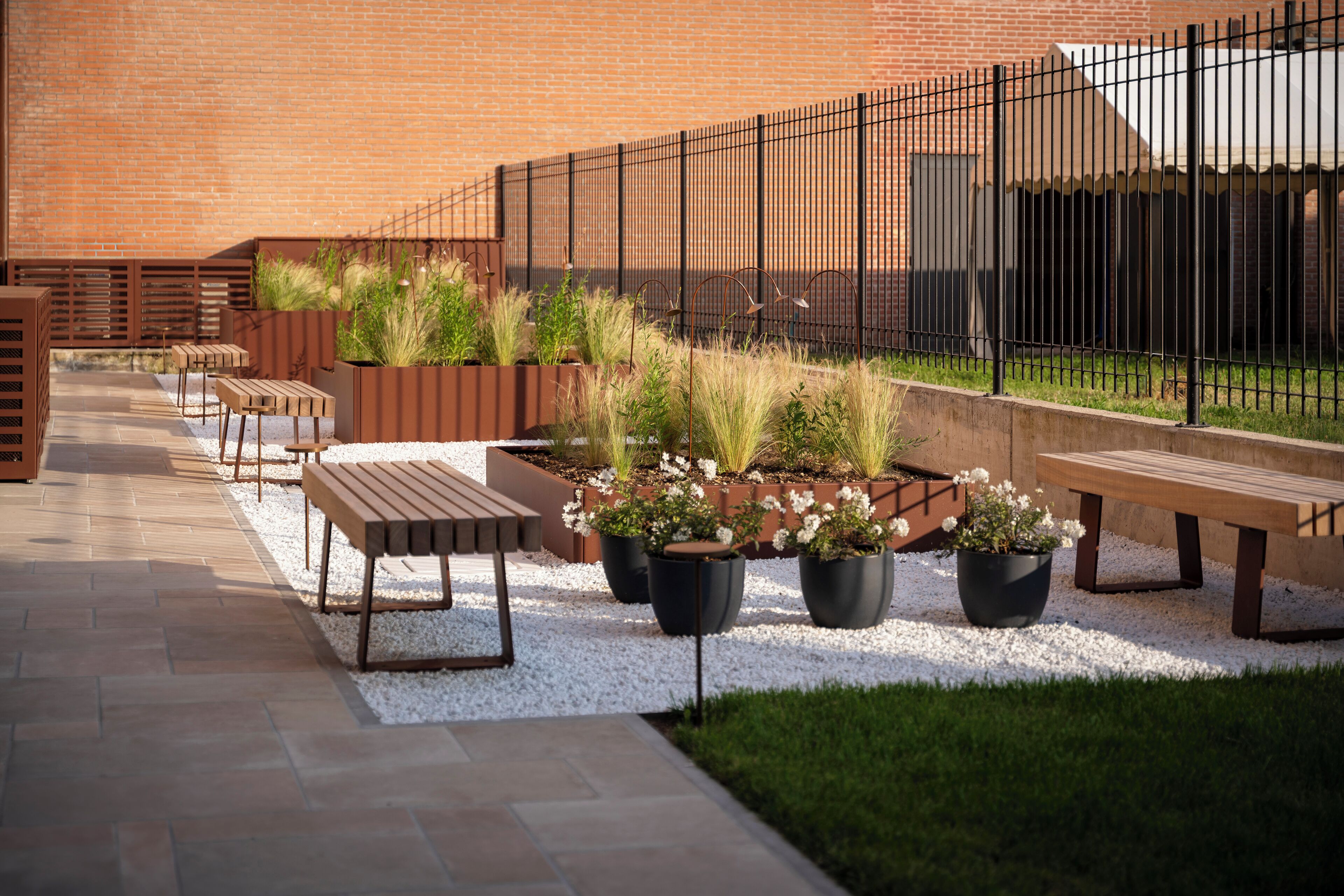 An outdoor seating area with benches and planters against a brick wall.