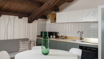 A modern kitchen with a round dining table, white chairs, and a hanging light fixture.