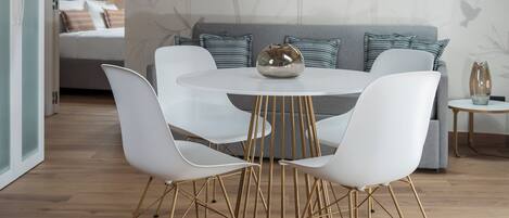 A dining area with a round table, white chairs, and a wooden ceiling.