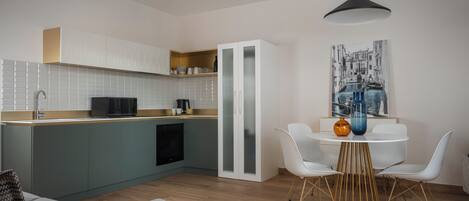 Una cocina moderna con comedor, que incluye una mesa blanca con sillas, una lámpara colgante y una isla de cocina con microondas y armarios.