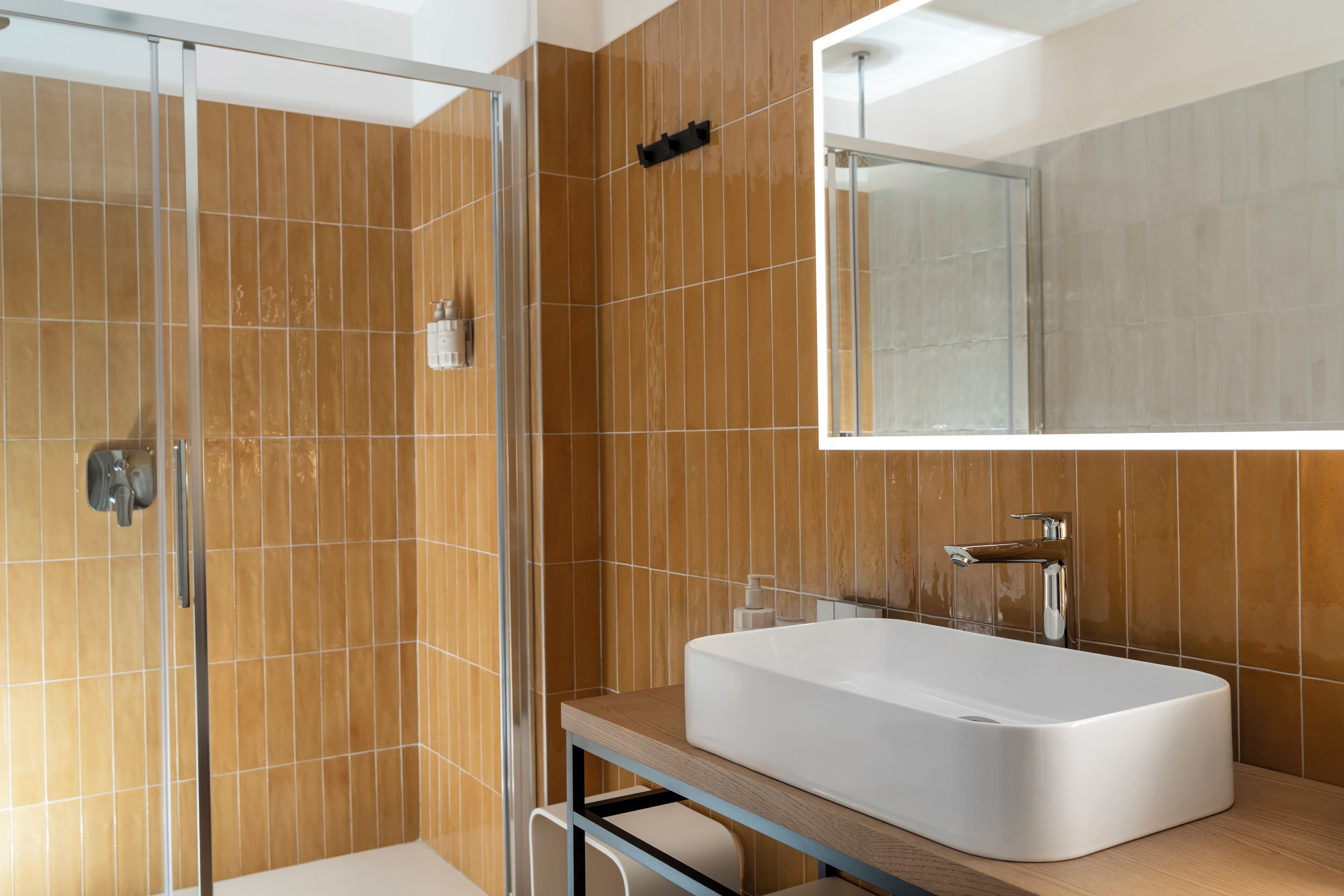 Une salle de bain moderne avec une douche à l’italienne en verre, un grand lavabo rectangulaire et un miroir au-dessus du lavabo.