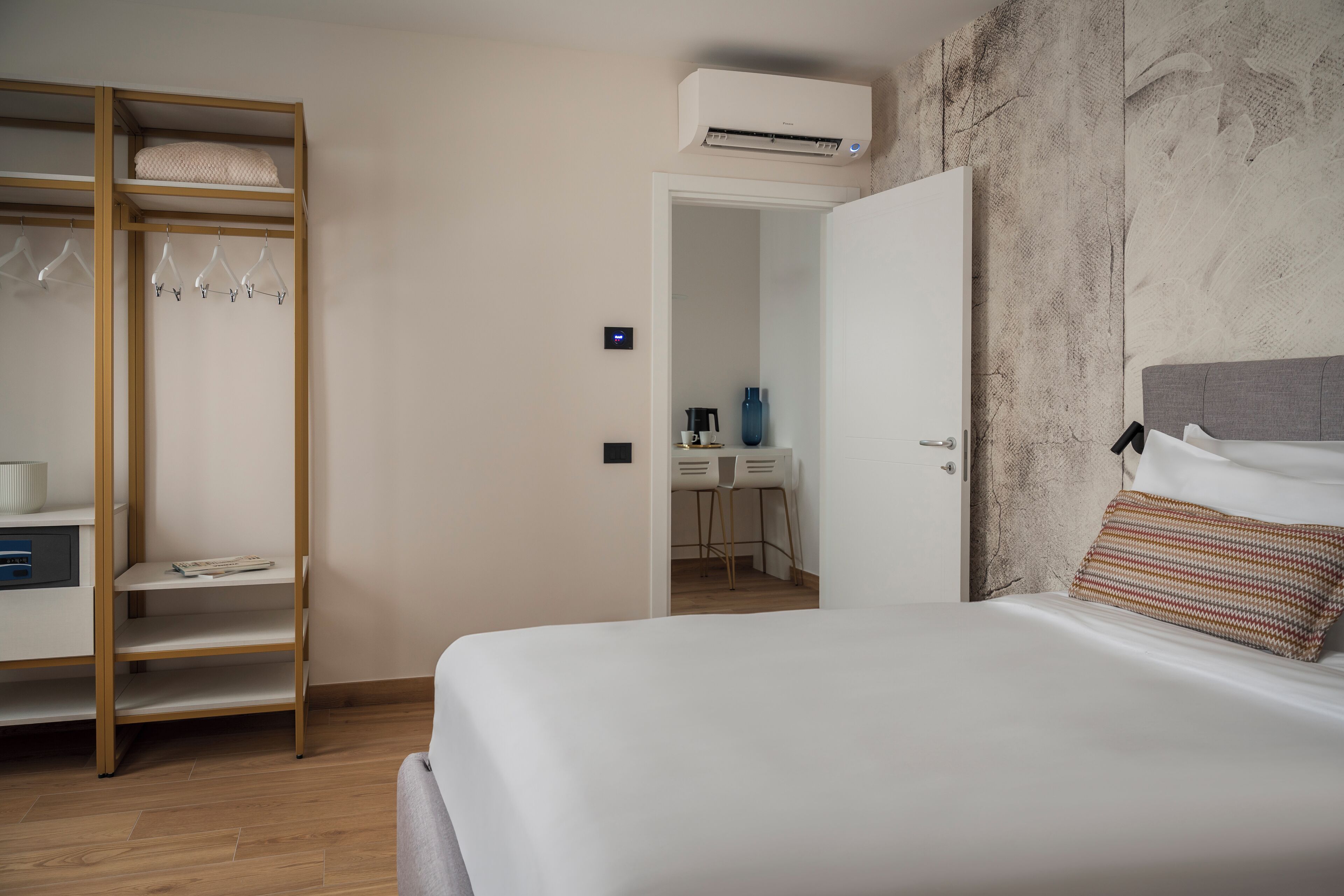 Un dormitorio con cama, armario, escritorio y sillas, y un equipo de aire acondicionado.