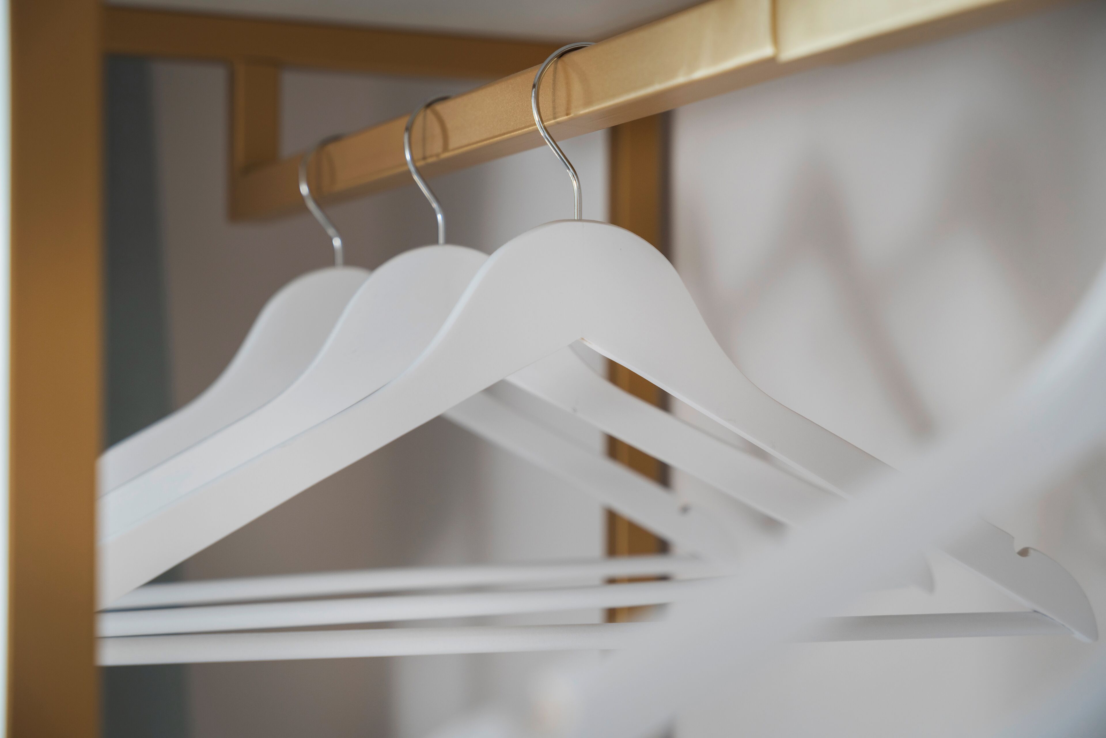 A wooden closet with white hangers and a wooden door.