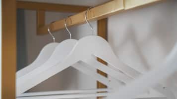 A wooden closet with white hangers and a wooden door.