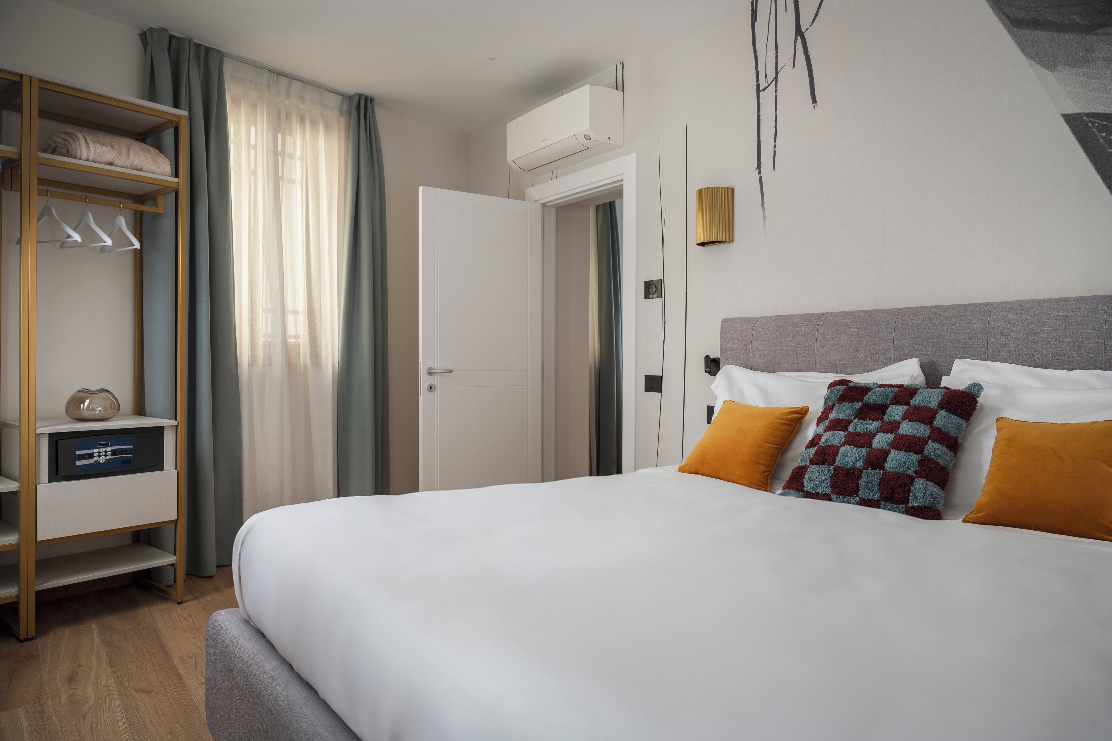 Una habitación de hotel con cama, armario, mesita de noche y aire acondicionado.