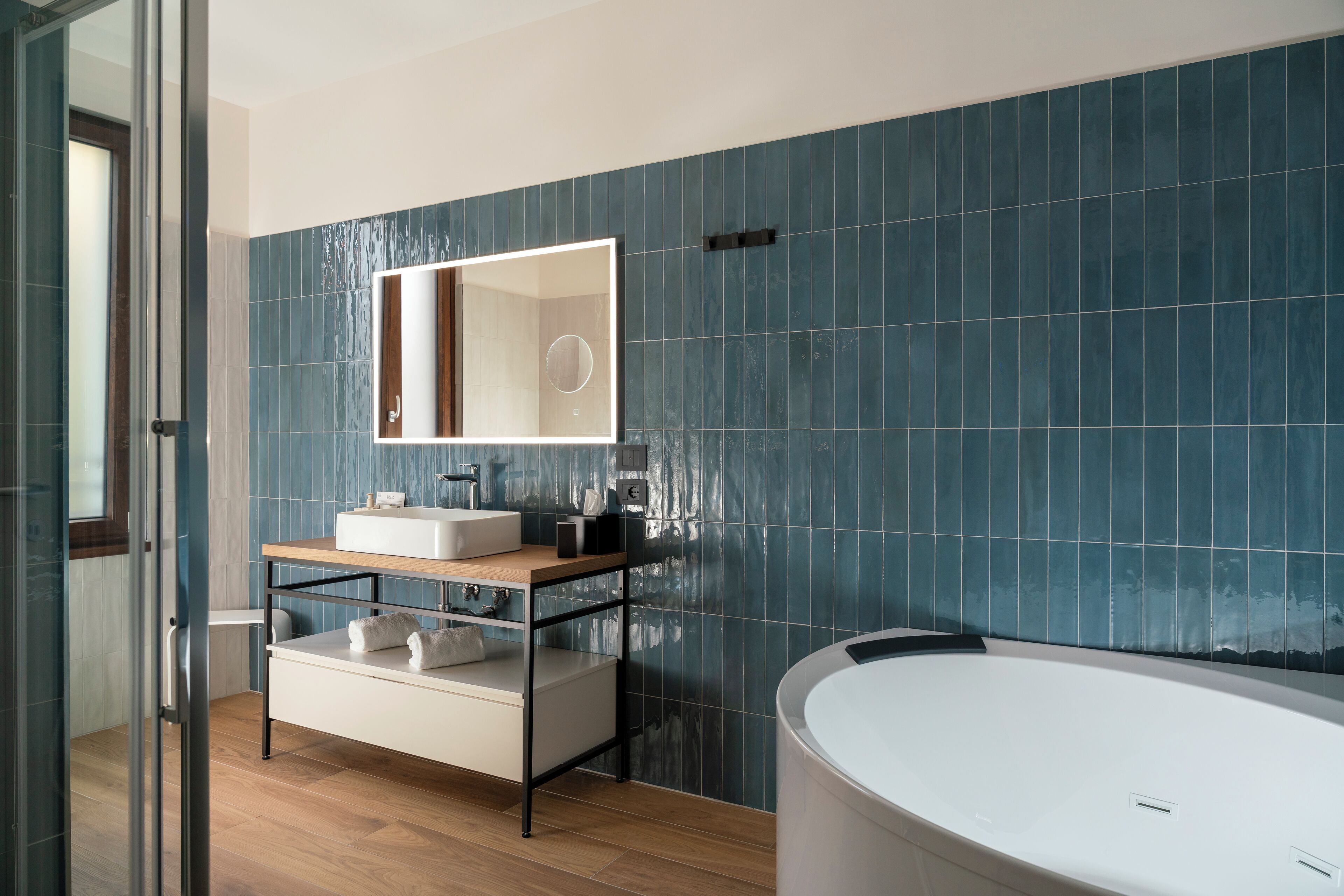 A modern bathroom with a large bathtub, a sink with a mirror, and a vanity with storage.