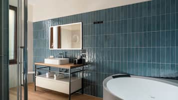 A modern bathroom with a large bathtub, a sink with a mirror, and a vanity with storage.