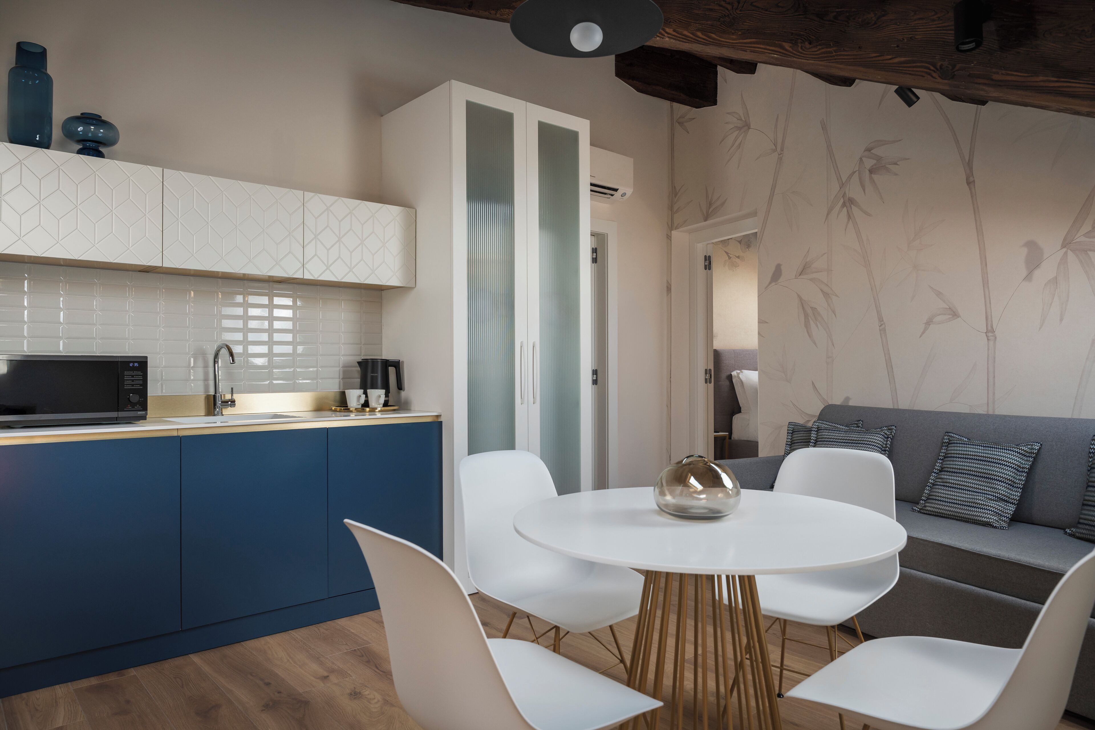 A modern kitchen with white cabinets, a blue countertop, and a round dining table with white chairs.