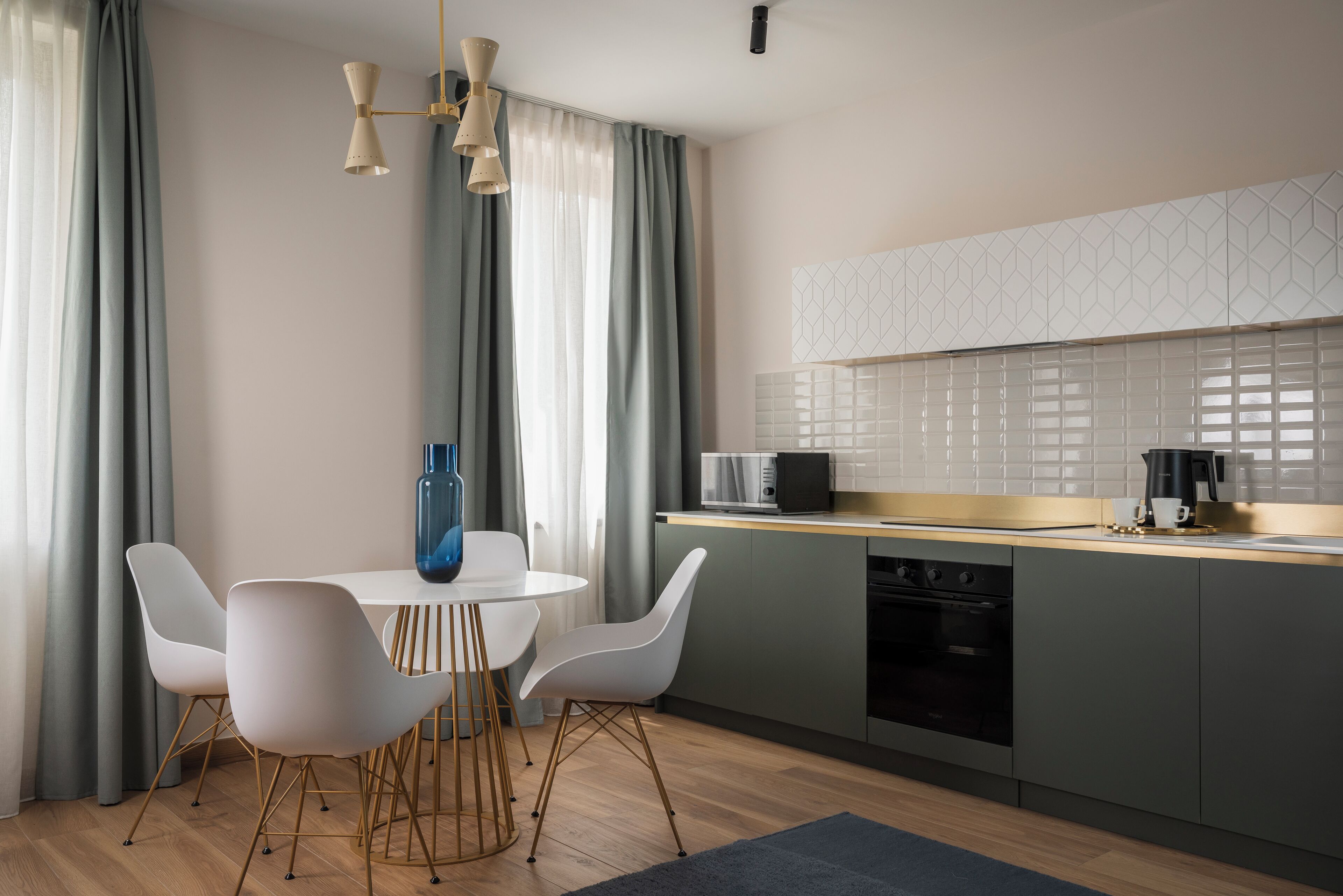 Una cocina moderna con una mesa de comedor redonda, sillas blancas y un jarrón azul.