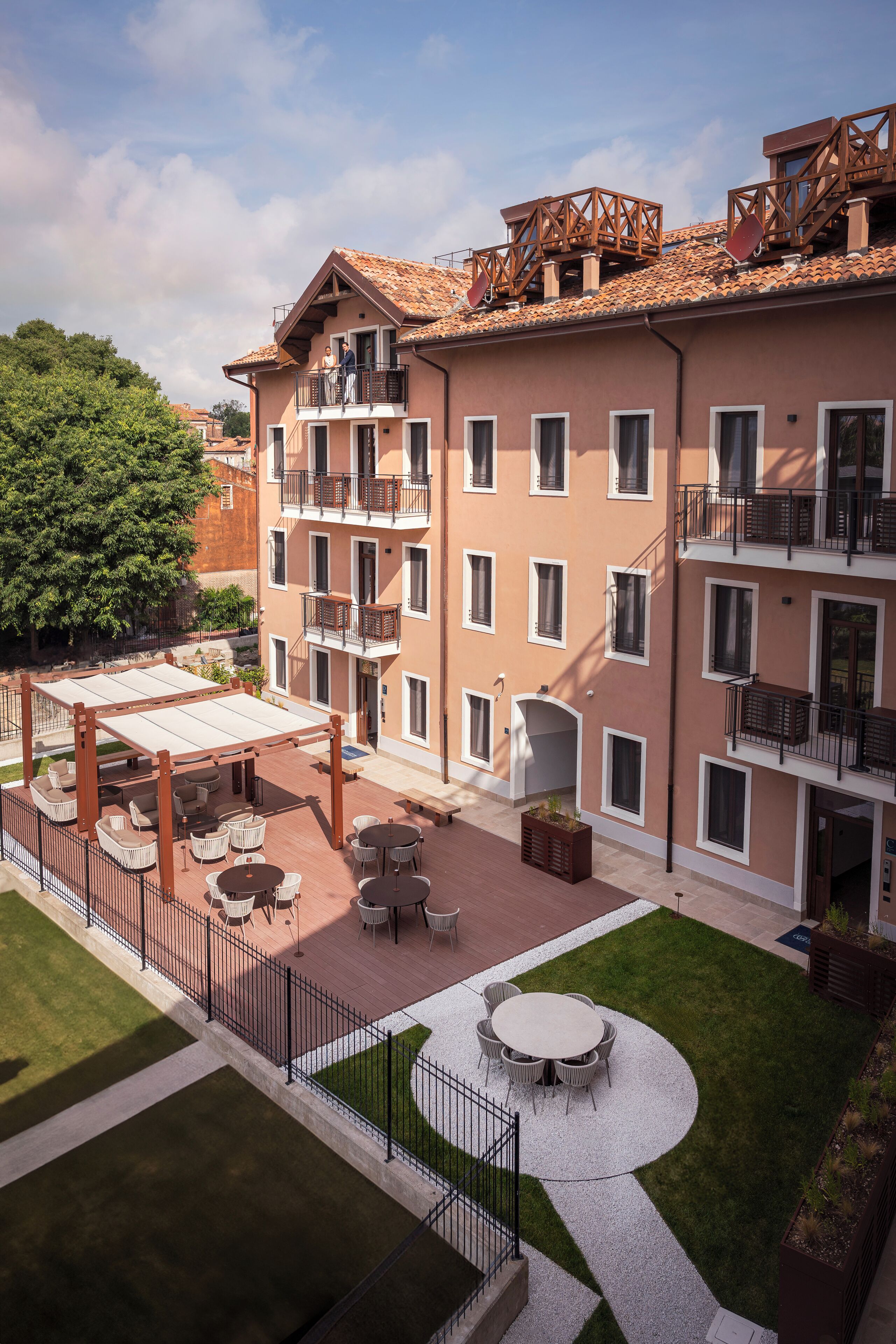 A multi-story building with balconies, outdoor seating, and a well-maintained courtyard.