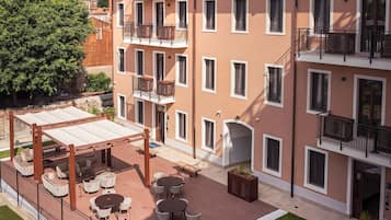 Un edificio de varios pisos con balcones, mobiliario exterior y un patio bien cuidado.