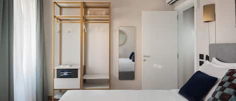 A modern bedroom with a bed, a wardrobe, a mirror, and an air conditioning unit.