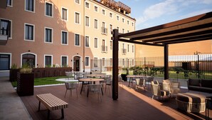 A courtyard with outdoor seating, a wooden bench, and a building with multiple windows and balconies. - Palazzo Dei Guardiani (Venice)