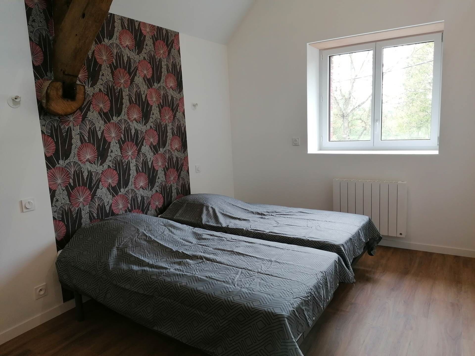 Een slaapkamer met twee bedden, een raam en een radiator.